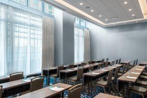 デンバーにあるAC Hotel by Marriott Denver Downtownのテーブルと椅子、窓が備わる広い客室です。