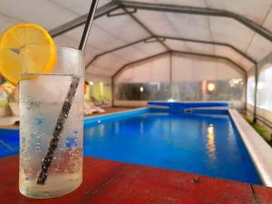 a drink with a lemon slice on a table next to a swimming pool at Hotel y Spa Termas del Este in Federación