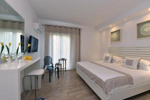 a white bedroom with a bed and a desk and a table at Apollon Boutique Hotel in Parikia