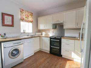 a kitchen with white cabinets and a washer and dryer at Powillimount Cottage in Dumfries