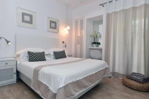 a white bedroom with a large bed with pillows at Apollon Boutique Hotel in Parikia