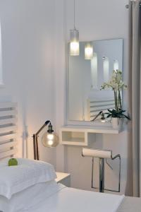 a white bedroom with a bed and a mirror at Apollon Boutique Hotel in Parikia