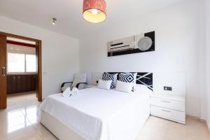 a white bedroom with a large white bed and a window at Villa Pla de l Era in Salou +40 photos
