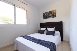 a bedroom with a bed with white sheets and a window at Villa Pla de l Era in Salou