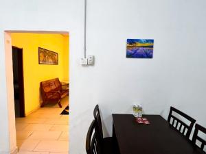 a dining room with a table and a yellow wall at Padang Besar White House Homestay in Padang Besar +25 photos