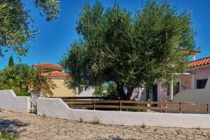 une clôture et un arbre devant une maison dans l'établissement Villa Penelope Periyali, à Vasilikos