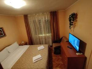 a hotel room with a bed and a desk with a television at Julie's Condo in Sinaia