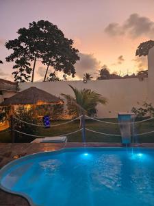 a large blue swimming pool with a sunset in the background at Casa veraneio in Itamaracá