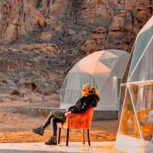 una persona seduta su una sedia su un palco di Traditions of Wadi Rum camp & jeep tour a Wadi Rum