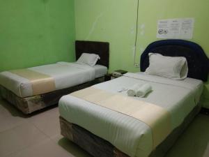two beds in a room with green walls at Hotel krui syariah in Krui