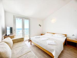 een witte slaapkamer met een bed en een balkon bij Apartments Tomo in Zaostrog