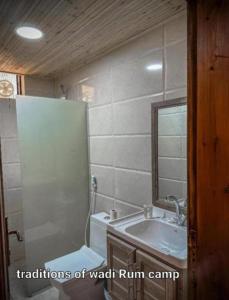a bathroom with a shower and a sink and a mirror at Traditions of Wadi Rum camp & jeep tour in Wadi Rum