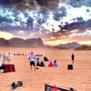 a group of people on a beach at sunset at Traditions of Wadi Rum camp & jeep tour in Wadi Rum