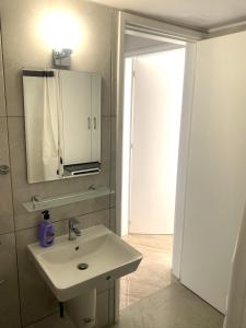 a bathroom with a sink and a mirror and a door at Mediterranean Apartments 2 in Paphos City