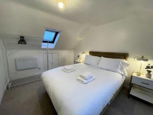 une chambre avec un grand lit blanc avec des serviettes dessus dans l'établissement Pass the Keys Beautifully Presented Cosy Town Centre Cottage, à Dumfries