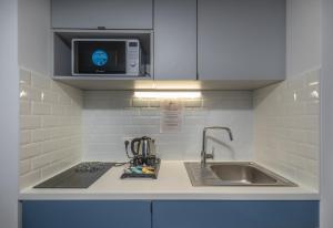 a kitchen counter with a sink and a microwave at The Originals Résidence Paris Sud Villejuif in Villejuif