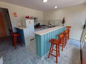 a kitchen with a counter with chairs and a refrigerator at Suites Mar Azul- São José - Maragogi in São José da Coroa Grande