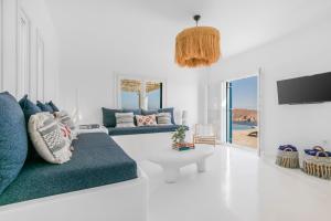a living room with a blue couch and a tv at Island Riviera Mykonos Villa in Agios Sostis Mykonos