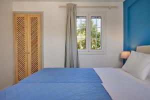 Dormitorio azul y blanco con cama y ventana en Villa Artemis Periyali, en Vasilikos