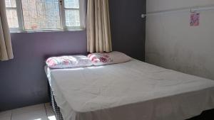 a small bed in a room with two pillows on it at Casa Espaçosa a 200m da praia in Florianópolis