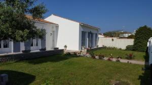 una casa blanca con un patio con césped verde en maison île de Ré avec piscine chauffée et vélos, en Le Bois-Plage-en-Ré