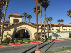 a building with palm trees in front of a street at Ramada by Wyndham Barstow in Barstow