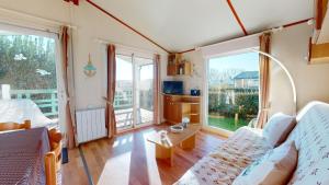 a living room with a couch and large windows at La Paranthese Marine in Brem-sur-Mer