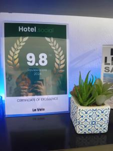 ein Schild für eine Hotelveranstaltung und eine Pflanze auf einem Regal in der Unterkunft Le Vele in Salerno