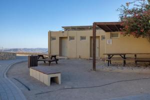 a group of picnic tables and benches in front of a building at SPNI Har Hanegev Field School in Mitzpe Ramon +14 photos