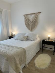 a bedroom with a white bed with a white blanket and a rug at Suite BA38 Departamento de Estilo en Microcentro in Paraná