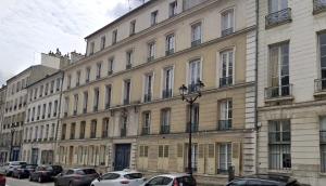 Un gran edificio con coches aparcados delante. en Le Grand Carré Versailles, en Versalles