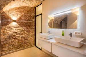 a bathroom with two sinks and a brick wall at Luxurious canal apartment in Utrecht A Location in Utrecht +23 photos