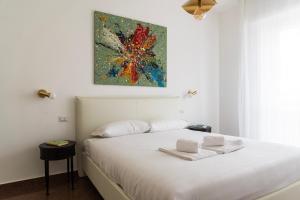 a bedroom with a white bed with a painting on the wall at Youhosty - Paul Valery Bis in Milan
