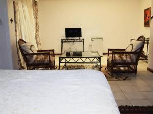 a bedroom with a bed and chairs and a television at The Landmark Boutique Hotel in Blantyre