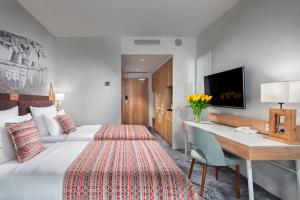 a hotel room with a bed and a desk at Hotel Aquarion Family & Friends - Destigo Hotels in Zakopane