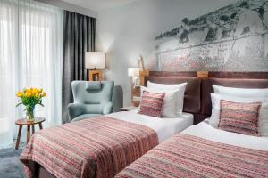 a hotel room with two beds and a blue chair at Hotel Aquarion Family & Friends - Destigo Hotels in Zakopane