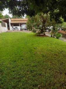 a green yard with a house in the background at Sítio do espeto in São Gonçalo do Pará