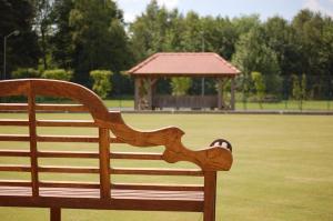 eine Holzbank in einem Park mit einem Pavillon in der Unterkunft Hollicarrs - Sunflower Lodge in York + 10 Fotos
