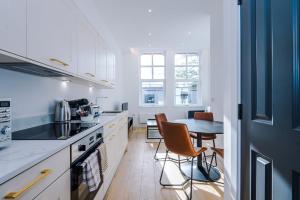 a kitchen with white cabinets and a table with chairs at Stylish 1-Bedroom Getaway in Sale in Sale
