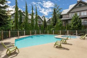 einen Pool mit Liegestühlen und ein Haus in der Unterkunft Northstar Whistler Village Resort in Whistler