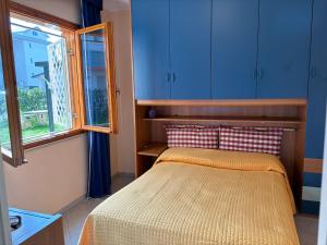 a bedroom with a bed with blue cabinets and a window at Villa Atlante in Bibione
