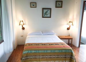 sypialnia z łóżkiem z dwoma światłami na ścianie w obiekcie Pacoche Lodge w mieście Pacoche