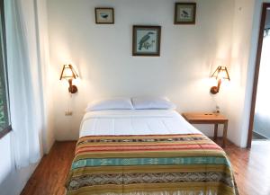 a bedroom with a bed with two lights on the wall at Pacoche Lodge in Pacoche