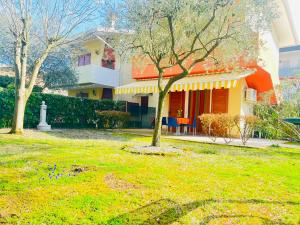a house with a tree in front of a yard at Villa Atlante in Bibione