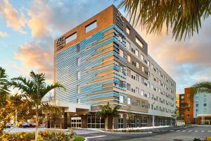 マイアミにあるAC Hotel by Marriott Miami Airport West/Doralの椰子の木の高い建物の描写
