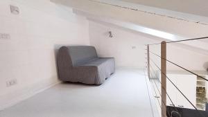 a gray chair sitting in a white room at Roma 17 in Cassina deʼ Pecchi