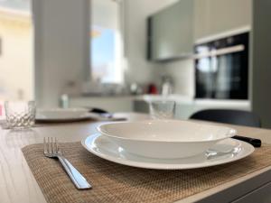 a white plate on a table with a fork and knife at Dione Casa Vacanze Donnalucata - Verde in Donnalucata +3 photos
