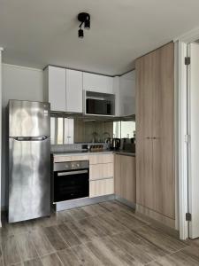 a kitchen with white cabinets and a stainless steel refrigerator at Laguna del Mar, Playa Arrecife in La Serena