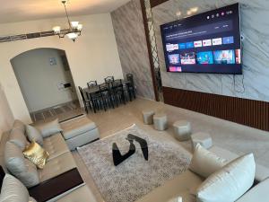 a living room with a couch and a flat screen tv at Spacious 3BR PLUS MAID ROOM in Sharjah