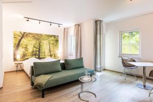 a living room with a green couch in front of a bed at Inselhotel Rügen in Göhren